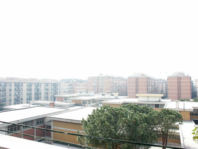 [Foto: La stessa inquadratura della foto precedente, ma allargata, genera la scomparsa completa del palazzo sullo sfondo dietro una densa cortina di smog]